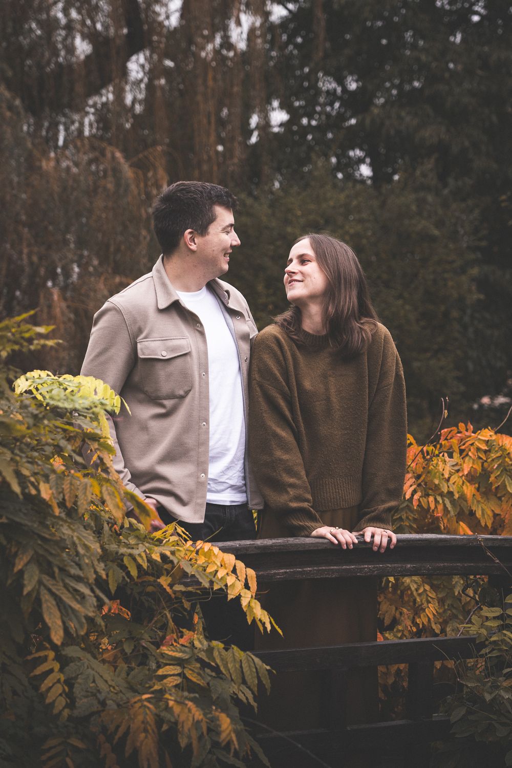 A romantic couple enjoying a moment together on a bench surrounded by autumn leaves.