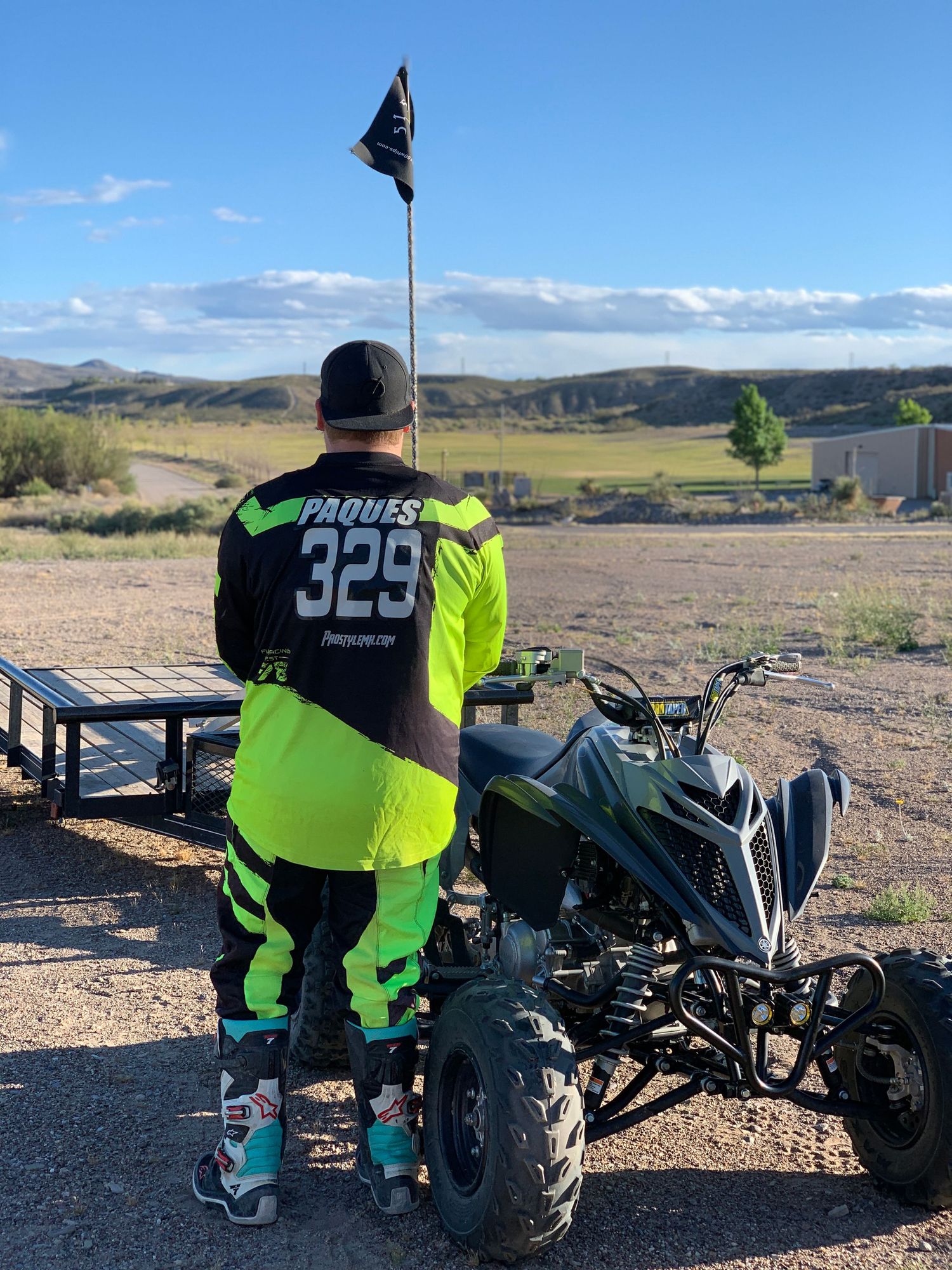 ATV rider in high-visibility gear standing at scenic overlook.