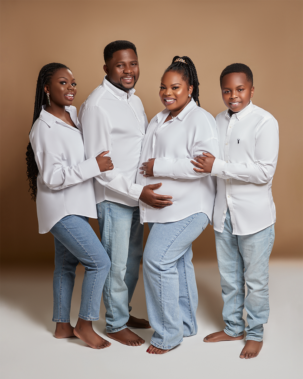 Group poses together wearing coordinated white tops and light denim in a studio portrait against a brown background.