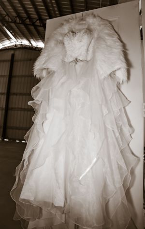 A fluffy white wedding dress with layers of tulle fabric photographed in dramatic lighting.