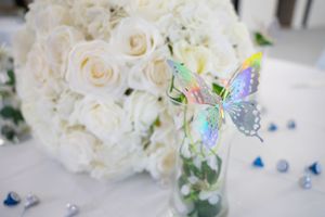 A romantic arrangement of white roses adorned with iridescent butterfly decorations.