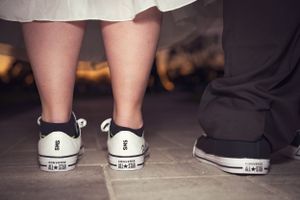 Close-up of wedding party shoes lined up on dark floor.