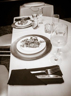 Elegant table settings with white plates and dark napkins in a formal dining room.