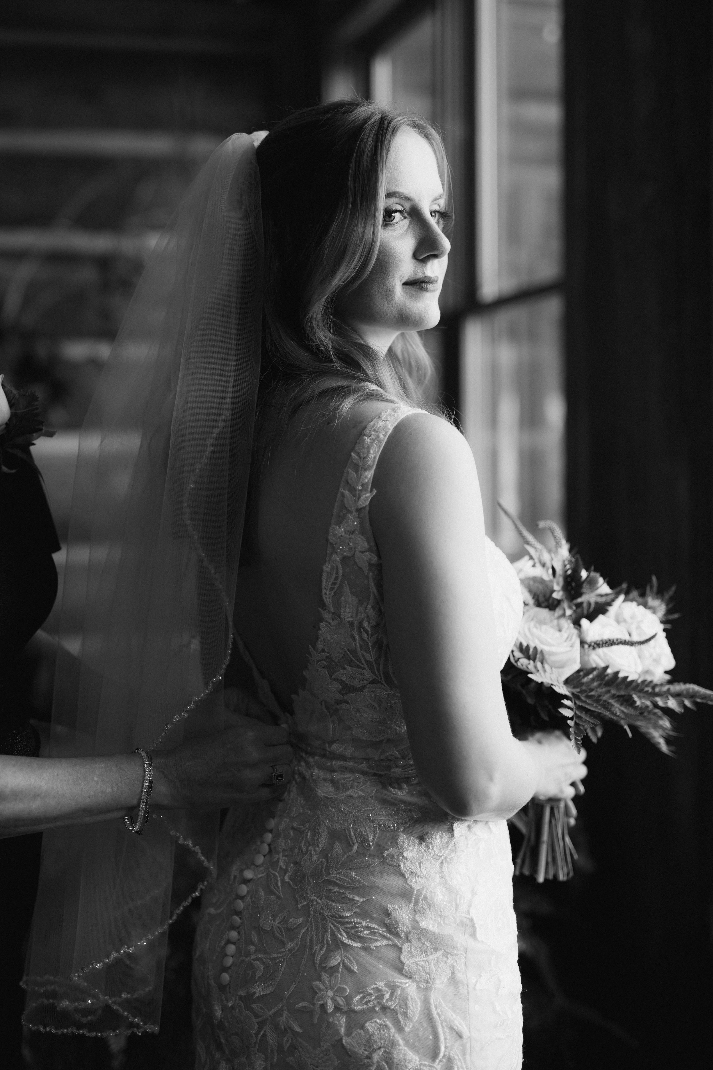 Dramatic black and white bridal portrait with lace details and bouquet.