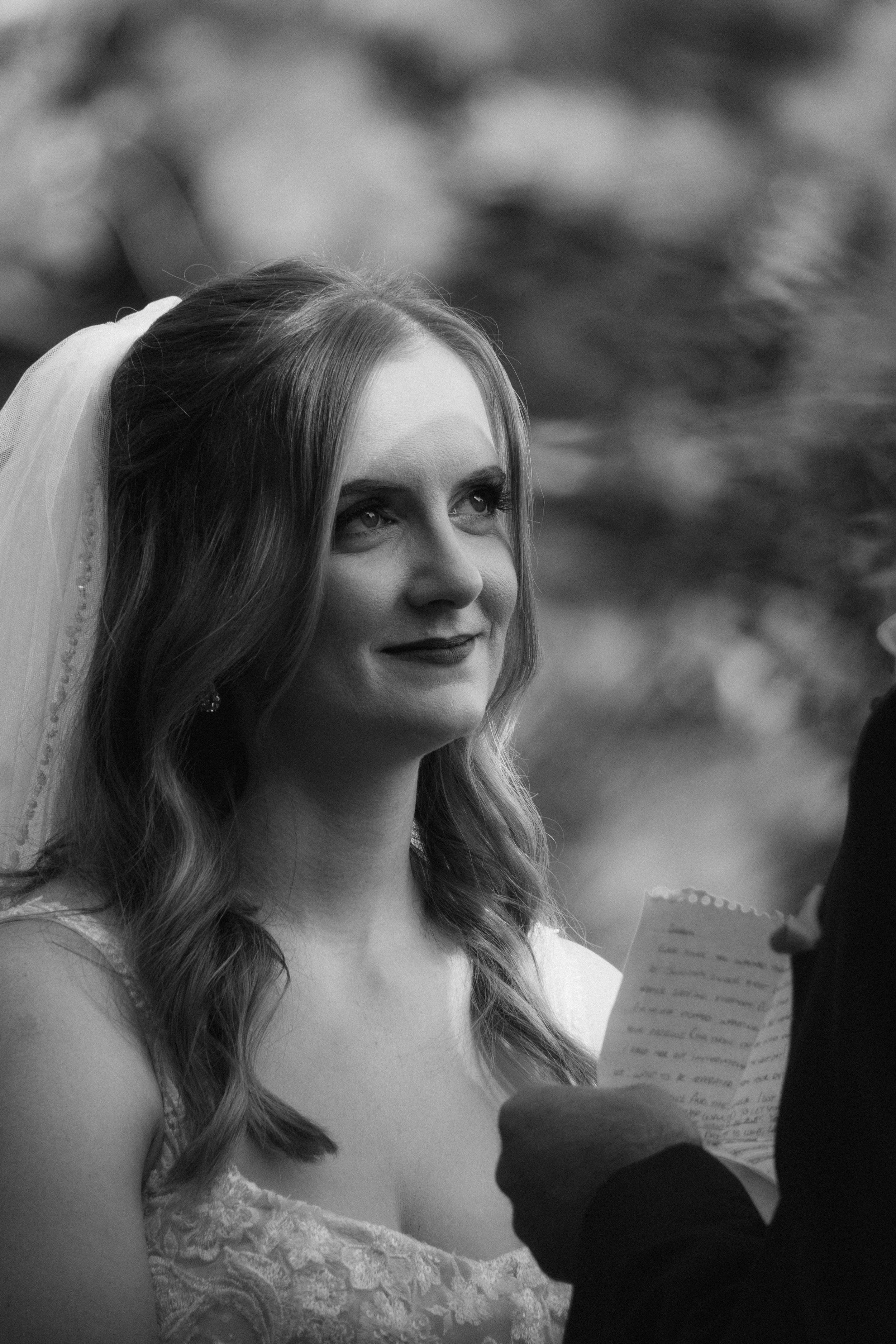 Artistic black and white portrait of bride reading letter in soft window light.