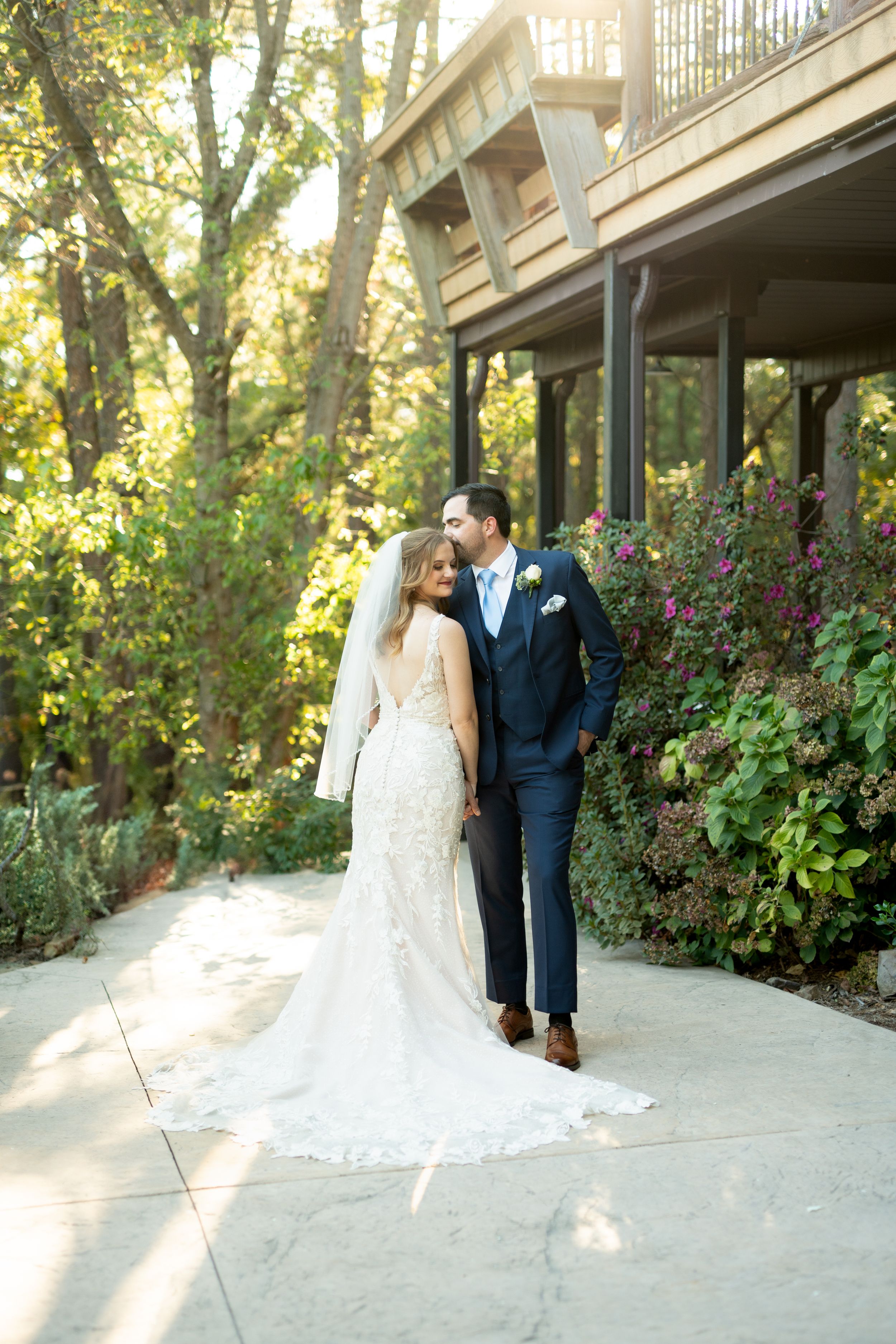 Wedding couple poses for romantic portraits along a garden path with lush greenery.