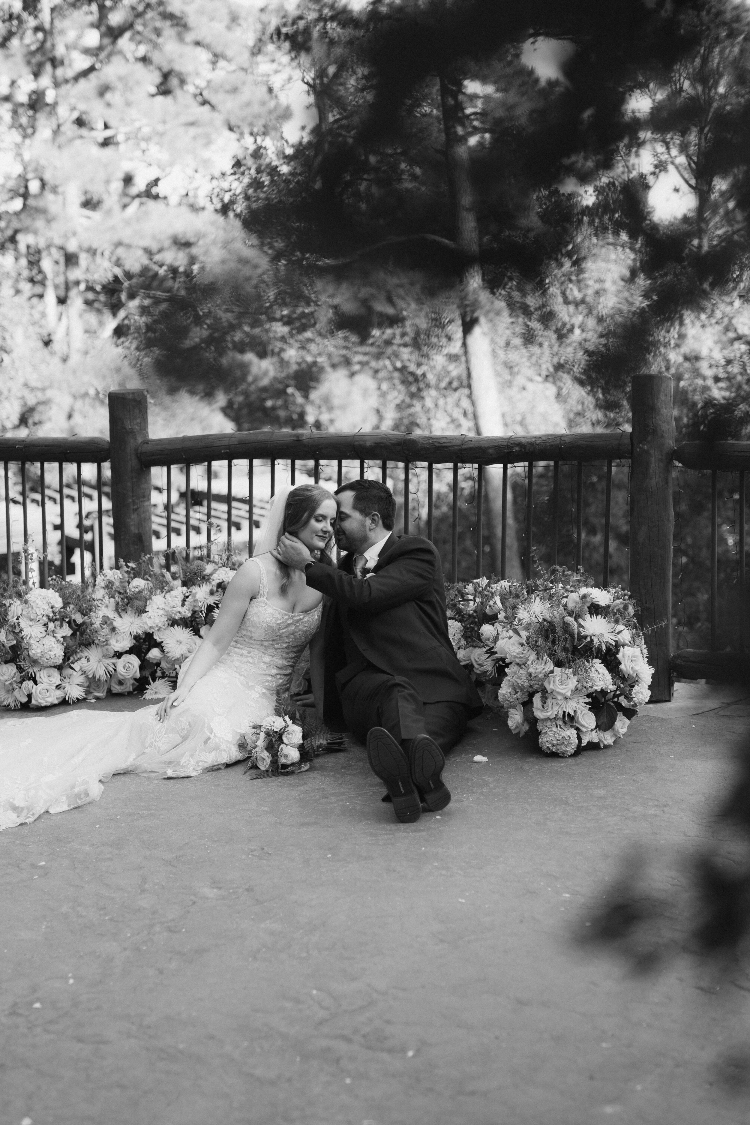 Black and white wedding photos showing a romantic moment against a floral backdrop.