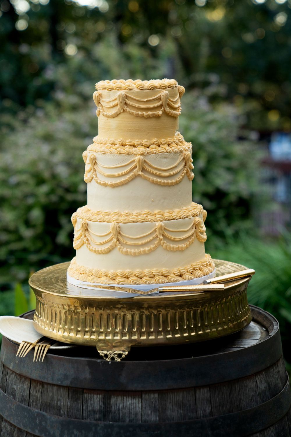 Elegant three-tiered wedding cake with delicate piped details on a gold platform.