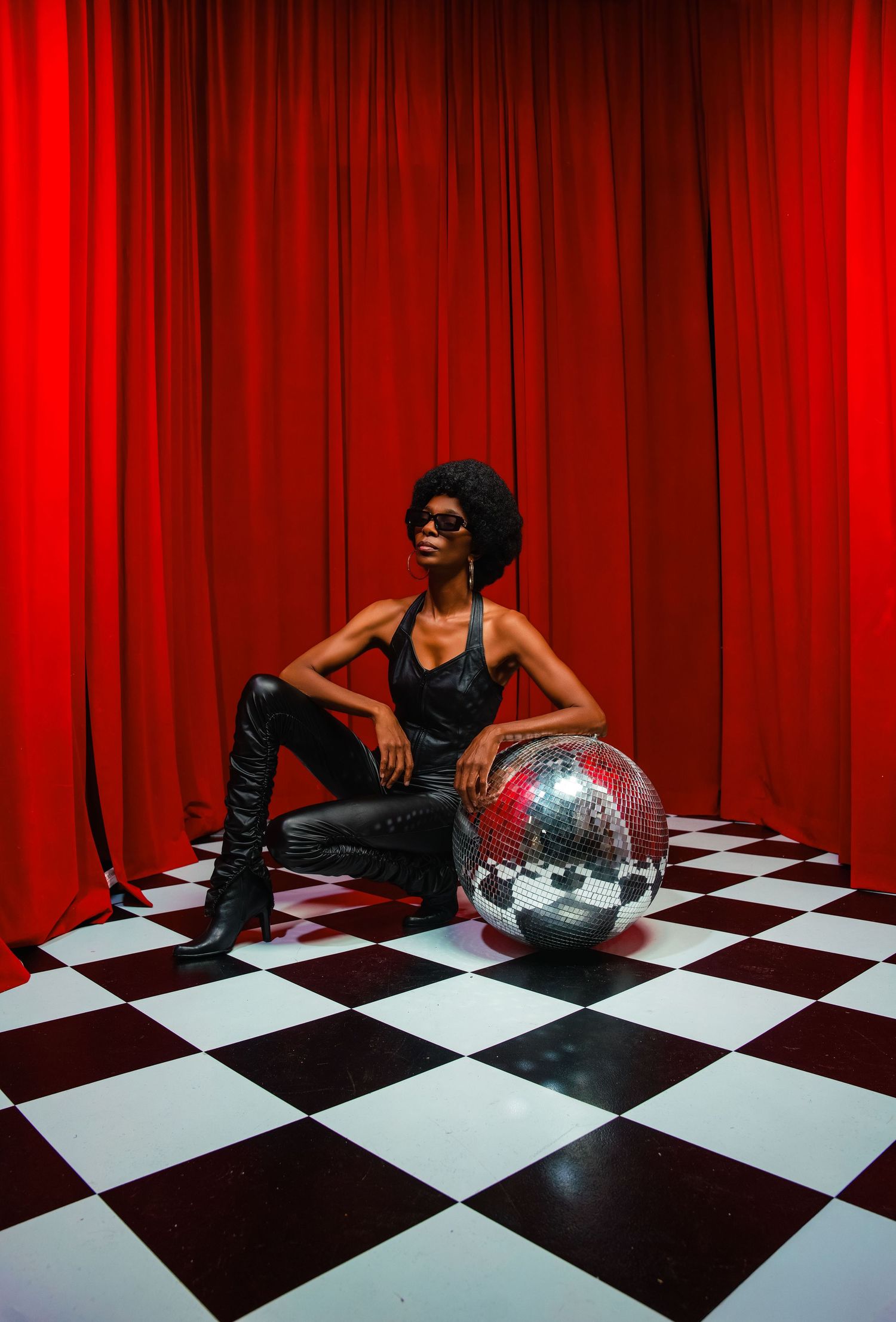 A festive party scene with sparkling disco balls against a vibrant red backdrop with a woman in a matching red jumpsuit.