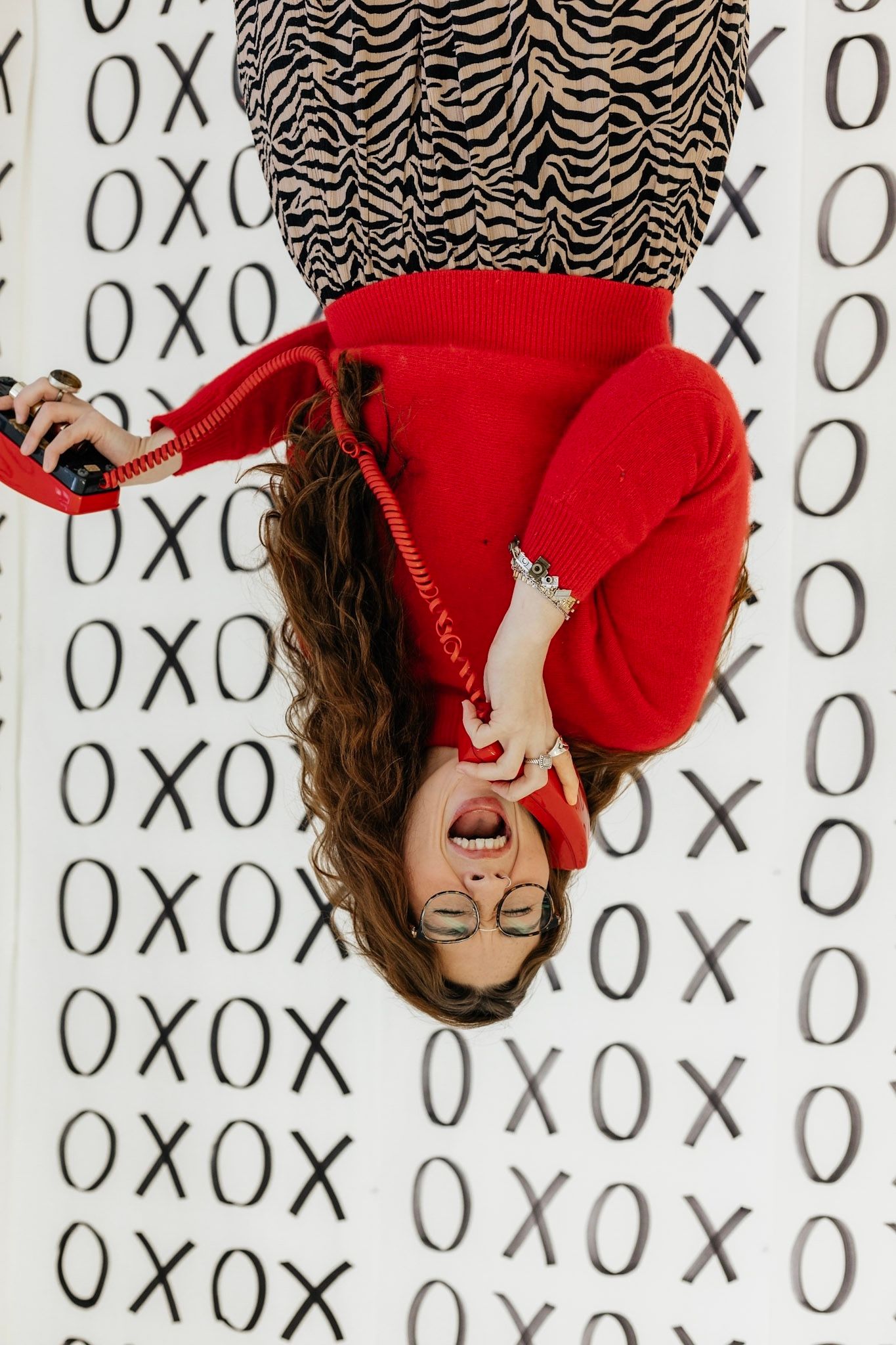 Creative portrait series against wall with XO pattern featuring red winter accessories.