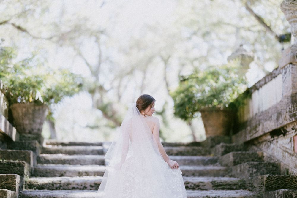 Ethereal bridal scene on stone steps with misty garden backdrop.