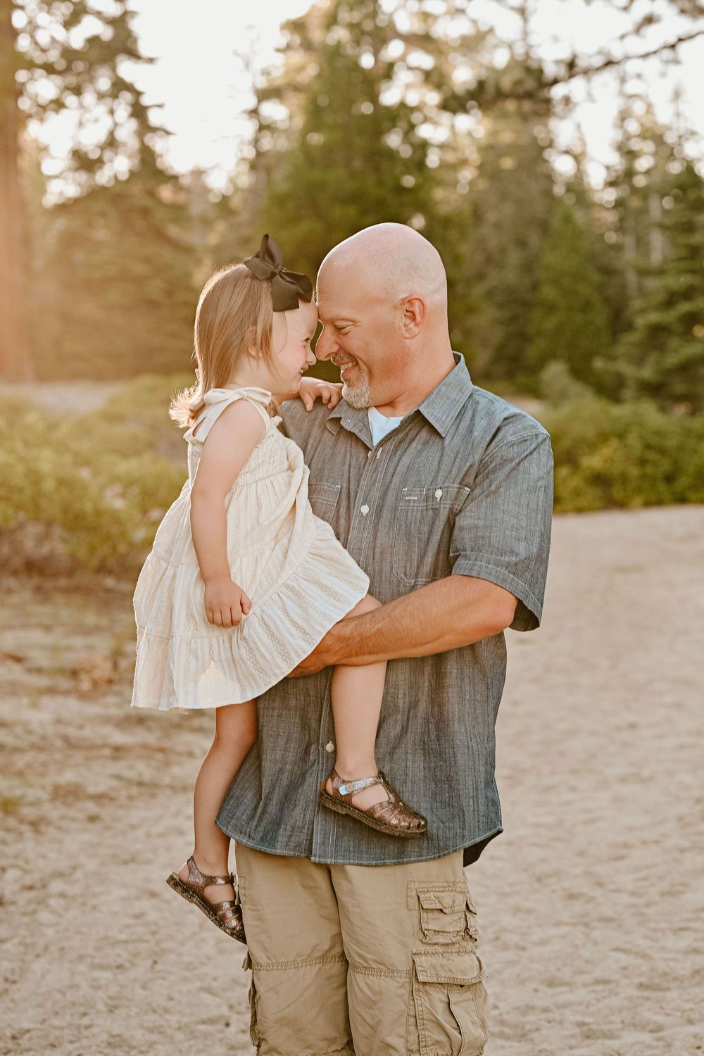A family embraces in a series of candid moments on a sandy beach during golden hour.