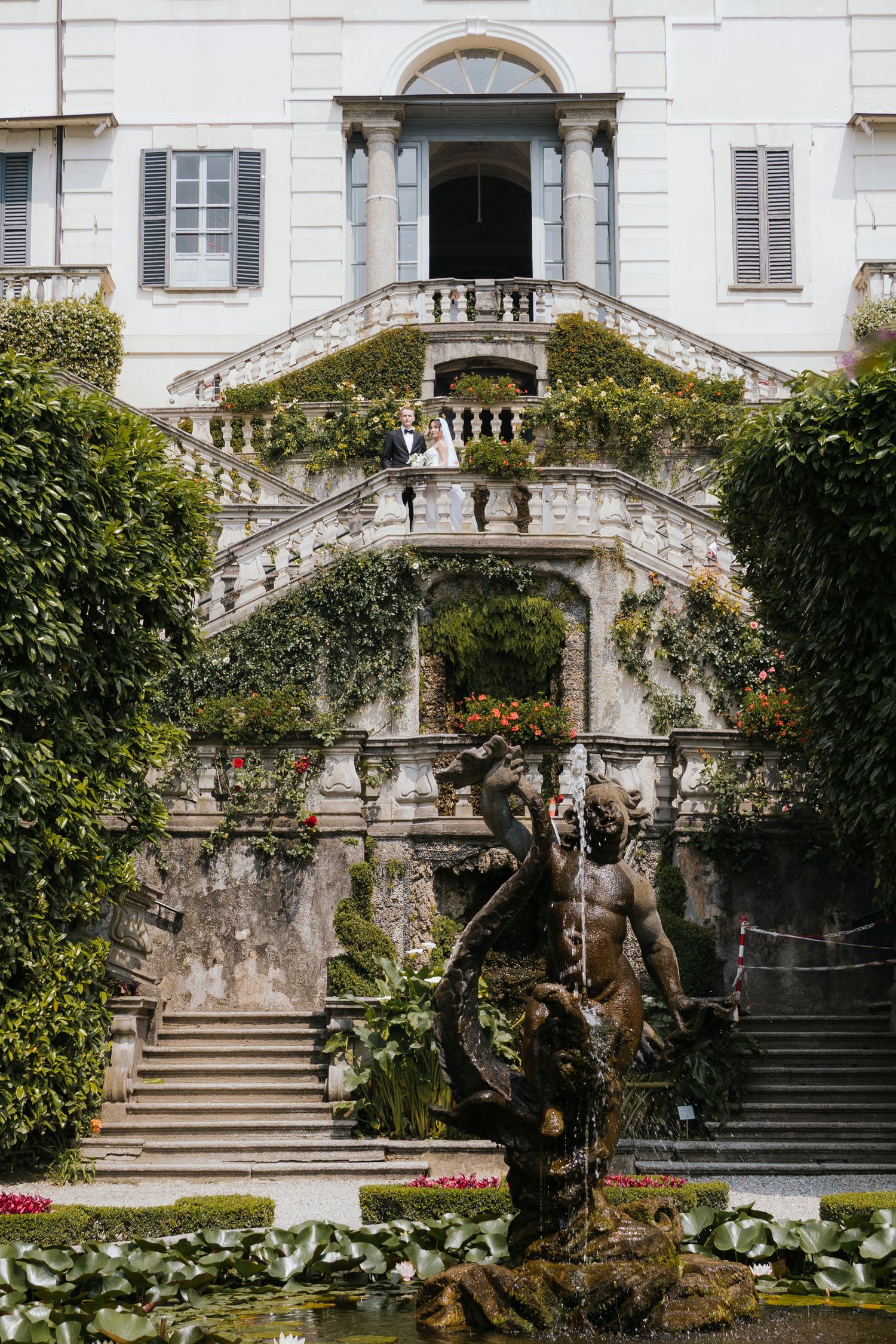 White historical building with ornate architecture sits among trees on a sunny day.
