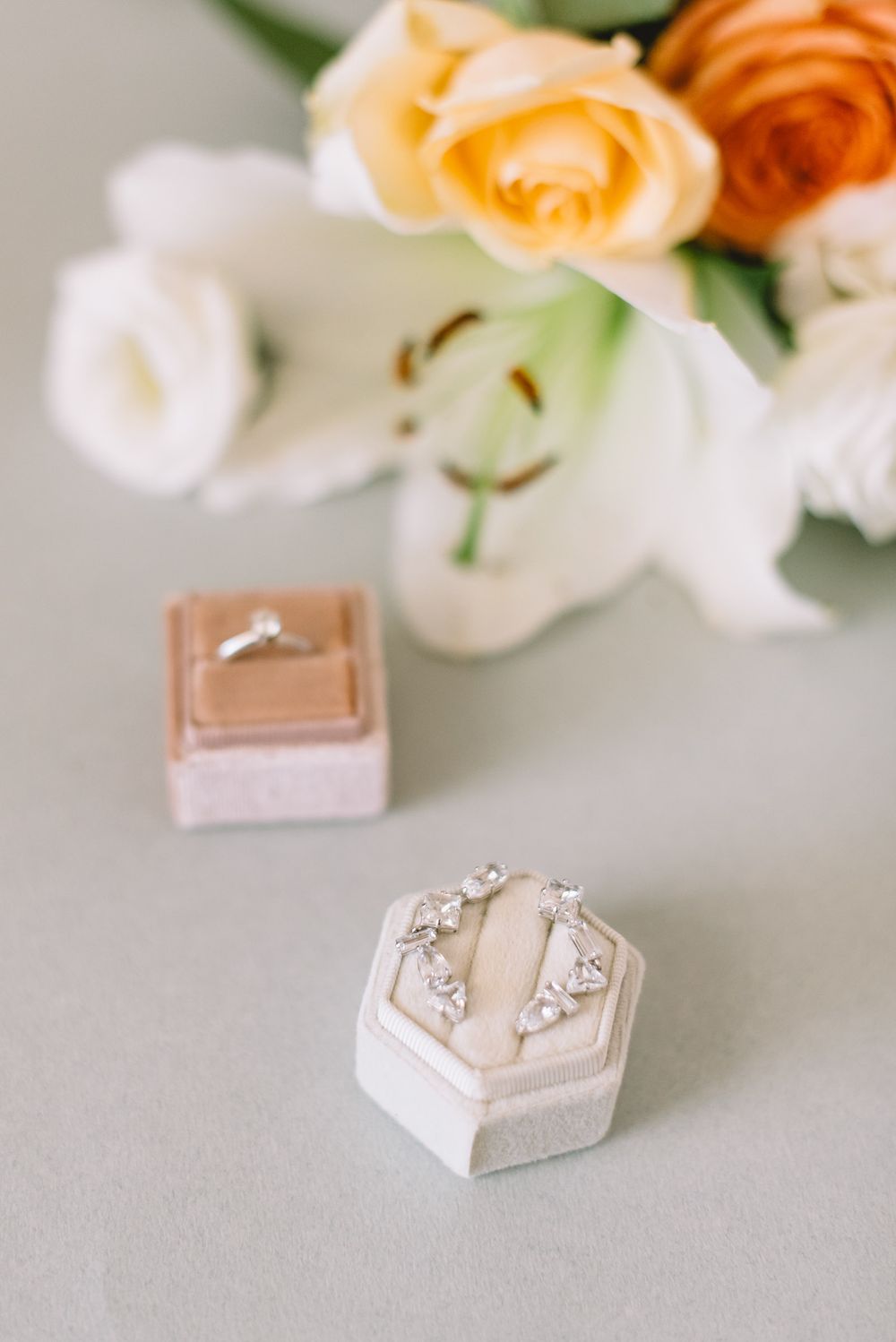 Elegant hexagonal ring boxes in cream and rose gold colors displayed with peach and white roses in the background.