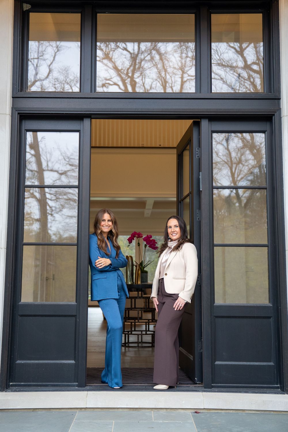 Healthcare workers in scrubs stand in doorways of a medical office building with large windows.