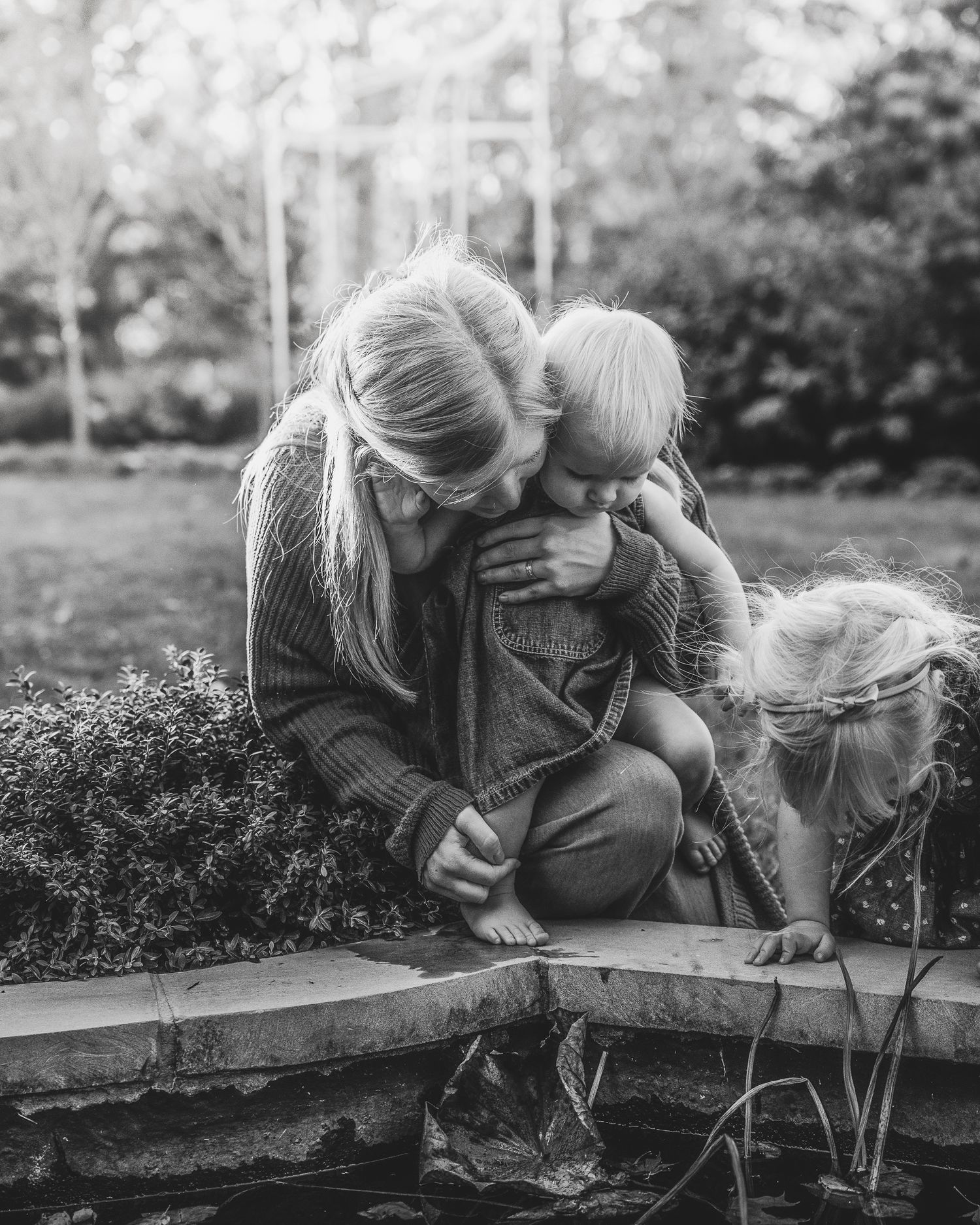 An intimate black and white portrait of a parent and child on an outdoor ledge.