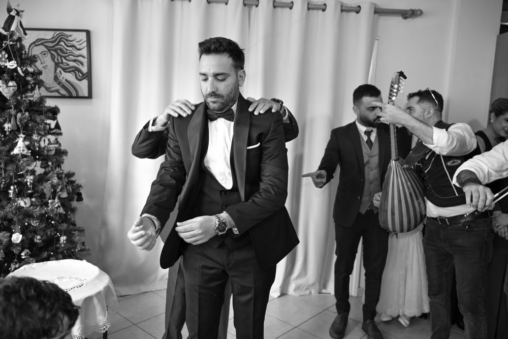 A black and white photo series shows groomsmen helping adjust formal attire before a wedding celebration.