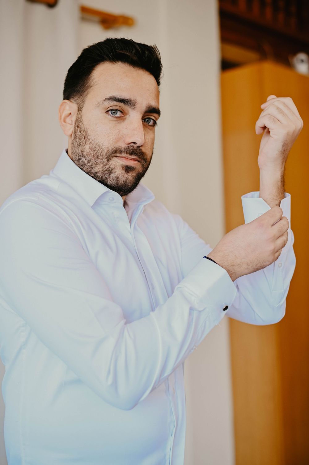 A sequence of images showing a person in a white dress shirt adjusting their sleeve cuff.
