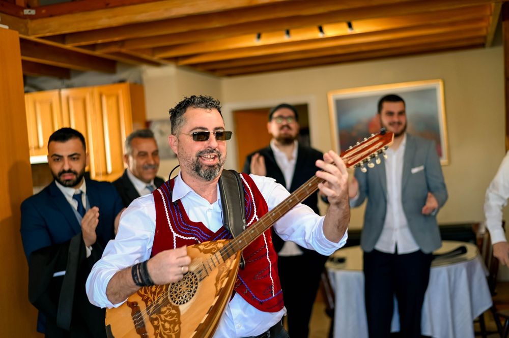 A group of musicians performing at a traditional event, wearing matching white shirts with red vests on stage.