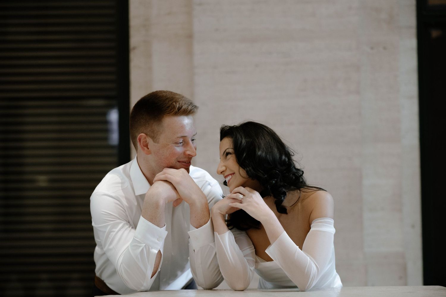 Candid romantic moment shows two people sharing a tender kiss against a neutral background.