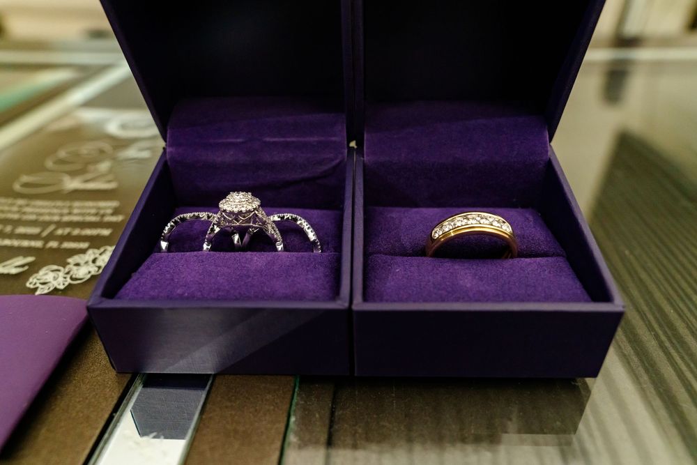 Two wedding rings nestled in purple velvet boxes shown side by side.