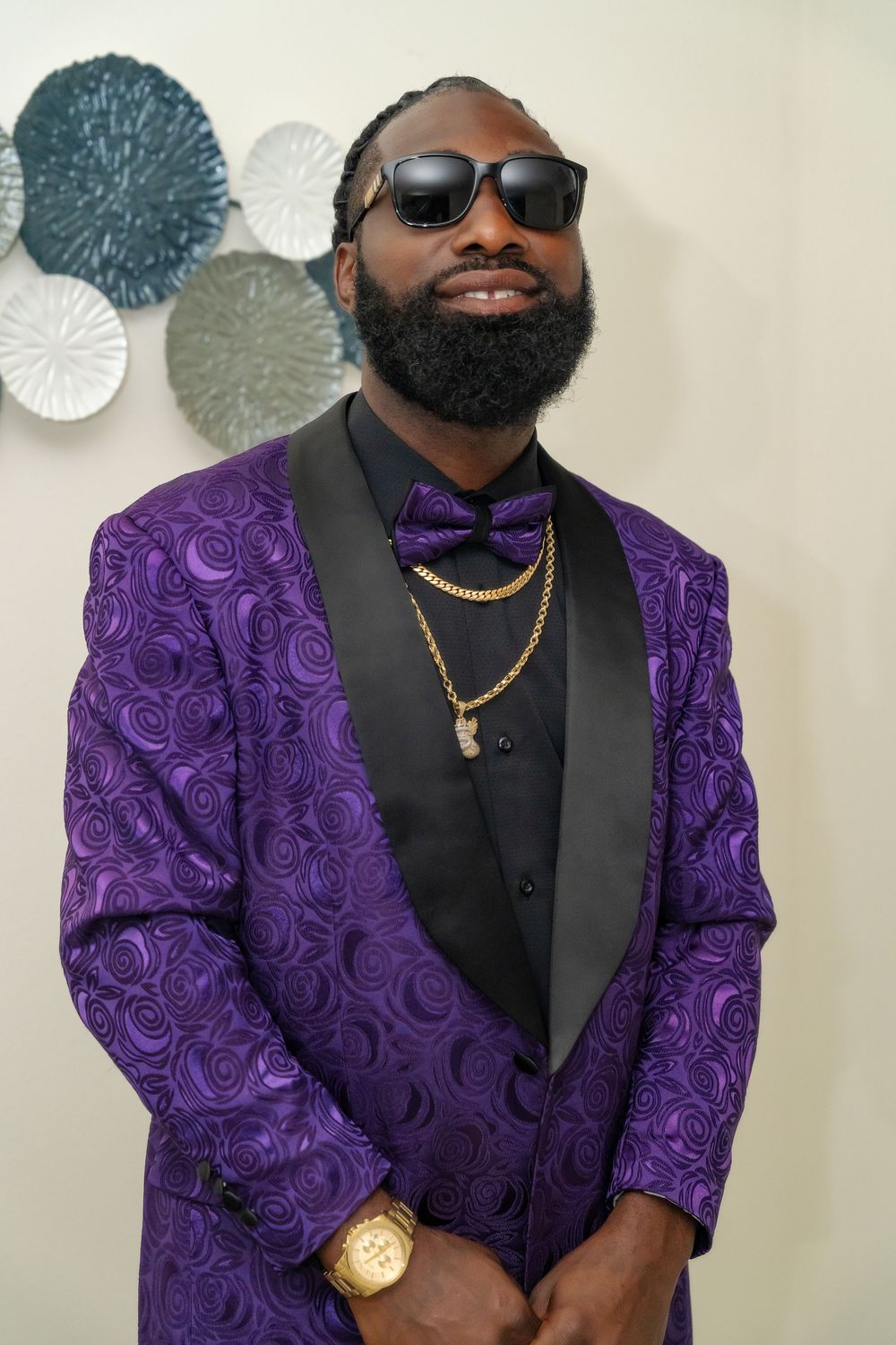 Groom wearing a stylish purple paisley tuxedo jacket with black lapels, bow tie and sunglasses.