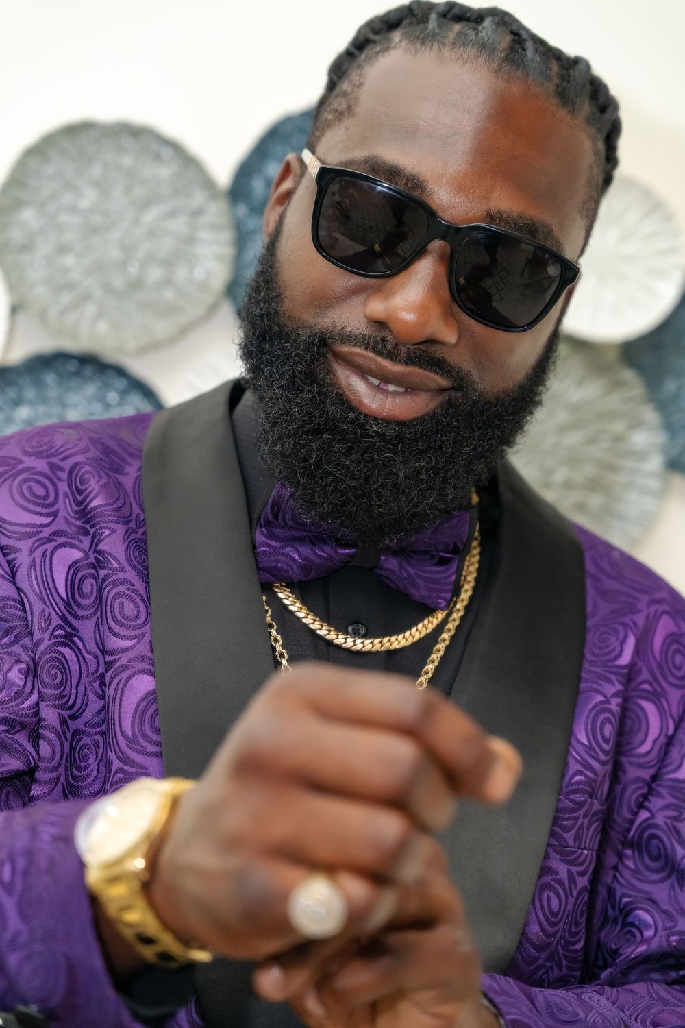 Close up portrait in purple tuxedo with gold accessories and full beard.