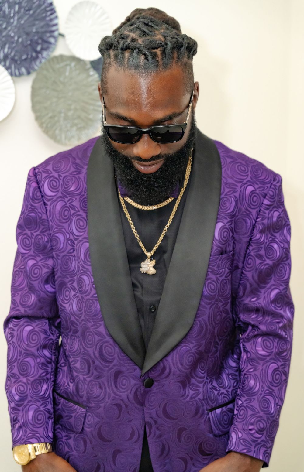 Detail shot of a purple textured jacket with black lapels and gold chain accessories.
