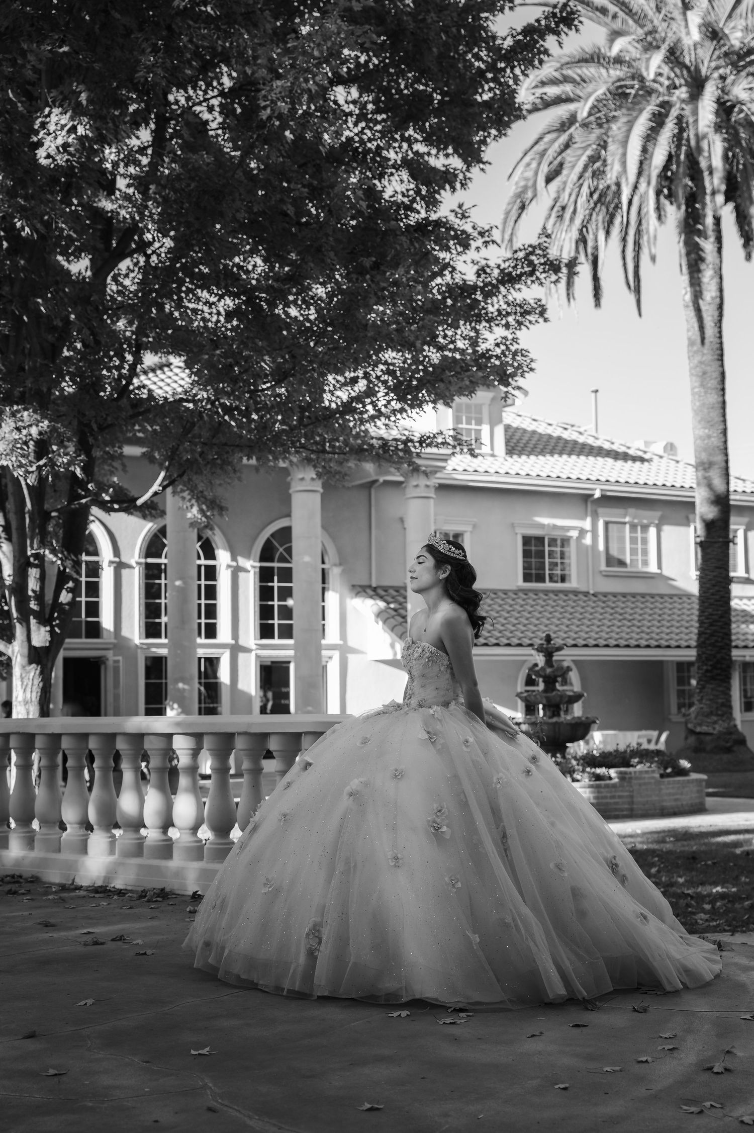 A black and white portrait of a quinceanera in an elegant white ballgown during photo session at her stunning quince venue