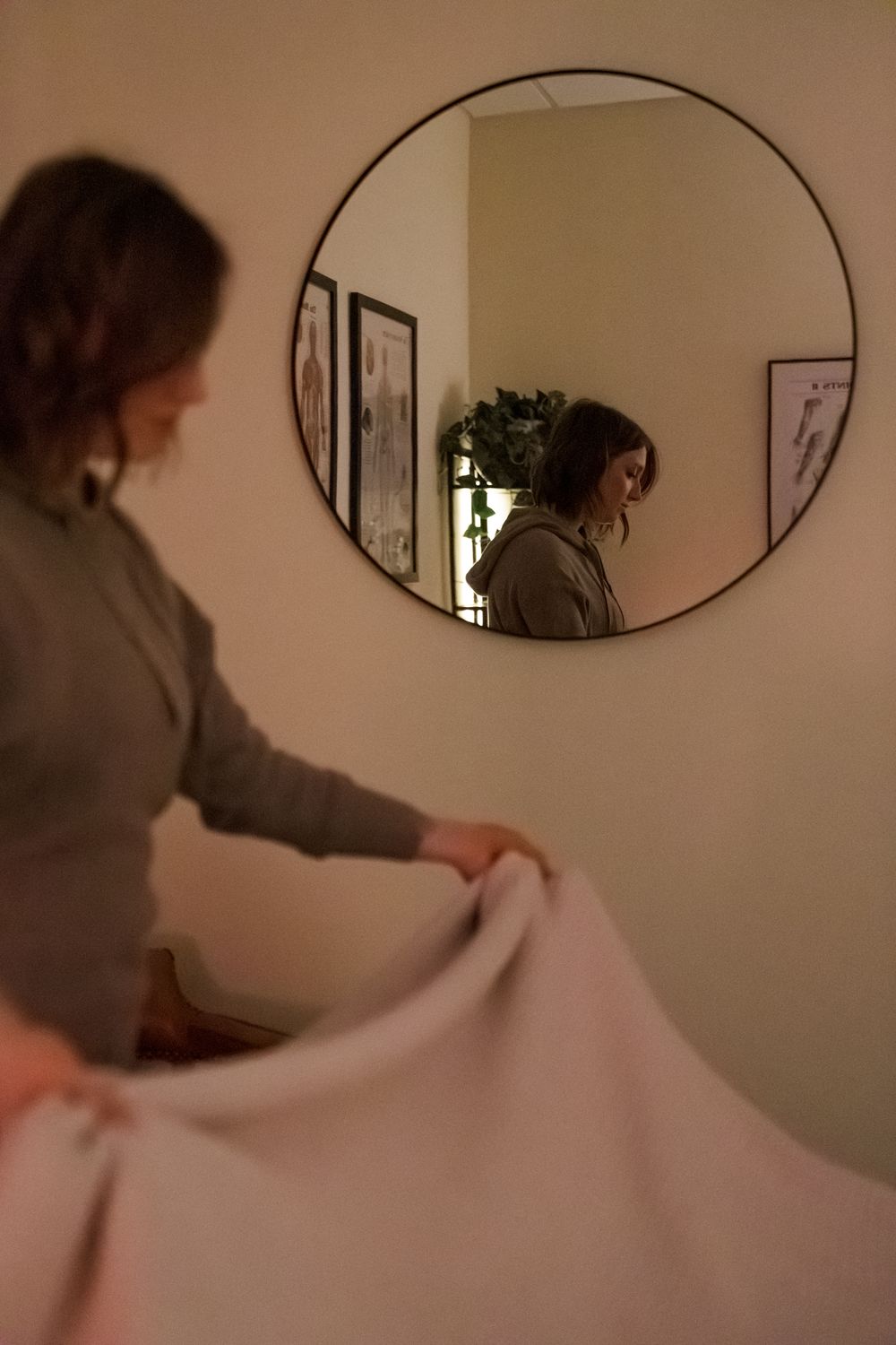 Reflection in round mirror shows treatment room setup with soft ambient lighting.