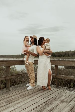 Two wedding couple figures sharing a special moment on a rustic wooden boardwalk overlooking a serene landscape at sunset.