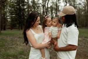 Intimate moments between two brides wearing white dresses sharing a gentle embrace in a wooded outdoor setting.