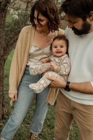 Family wearing casual clothing embraces together in a wooded outdoor setting during a lifestyle photoshoot.