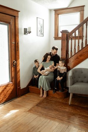 Sequence showing a woman and child interacting on a wooden staircase landing with a gray tufted chair against a white wall.