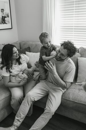 Black and white photo series showing a playful moment between two people relaxing together on a couch.