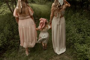 Vintage-inspired portrait showing flowy blush and cream dresses in a dreamy garden setting at golden hour.