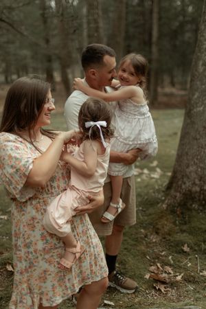 Family enjoying a tender moment together in a wooded setting wearing coordinated neutral and floral outfits.