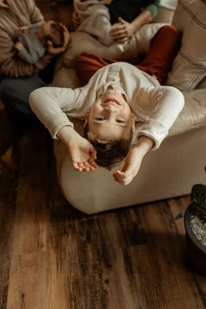 Person relaxing on a beige couch against wooden flooring in warm, moody lighting.