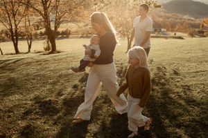 Family walking together through a sun-drenched grassy field on an autumn afternoon.