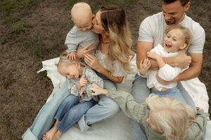 A family wearing casual clothes sits together on grass sharing tender moments in a series of connected photos.