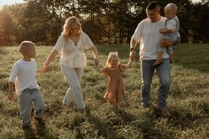 Family walking together through a sunlit meadow at golden hour, captured in a series of connected photos.