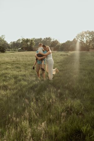 A romantic sunset moment captured in a golden meadow with sunlight streaming through trees in the background.