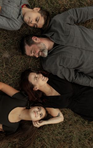 Two people lying on grass in dark clothing with their heads close together in a series of intimate portrait shots.