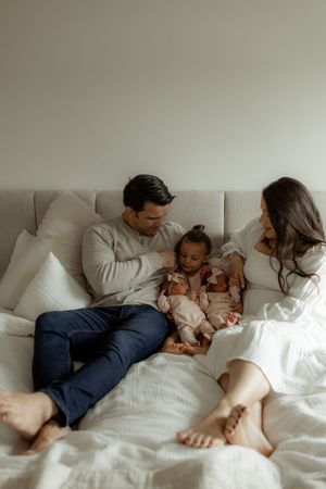 A series of intimate black and white photos showing a family relaxing together on a white bed.