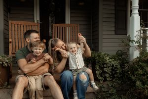 A series of candid black and white family photos showing tender moments between parents and children on a porch.