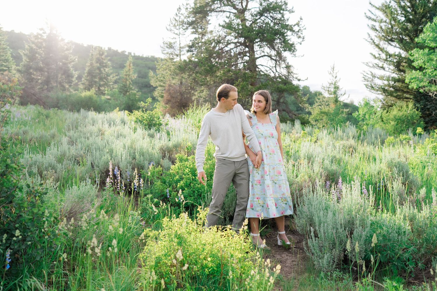 guy and girl walking through lush greenery looking at each other