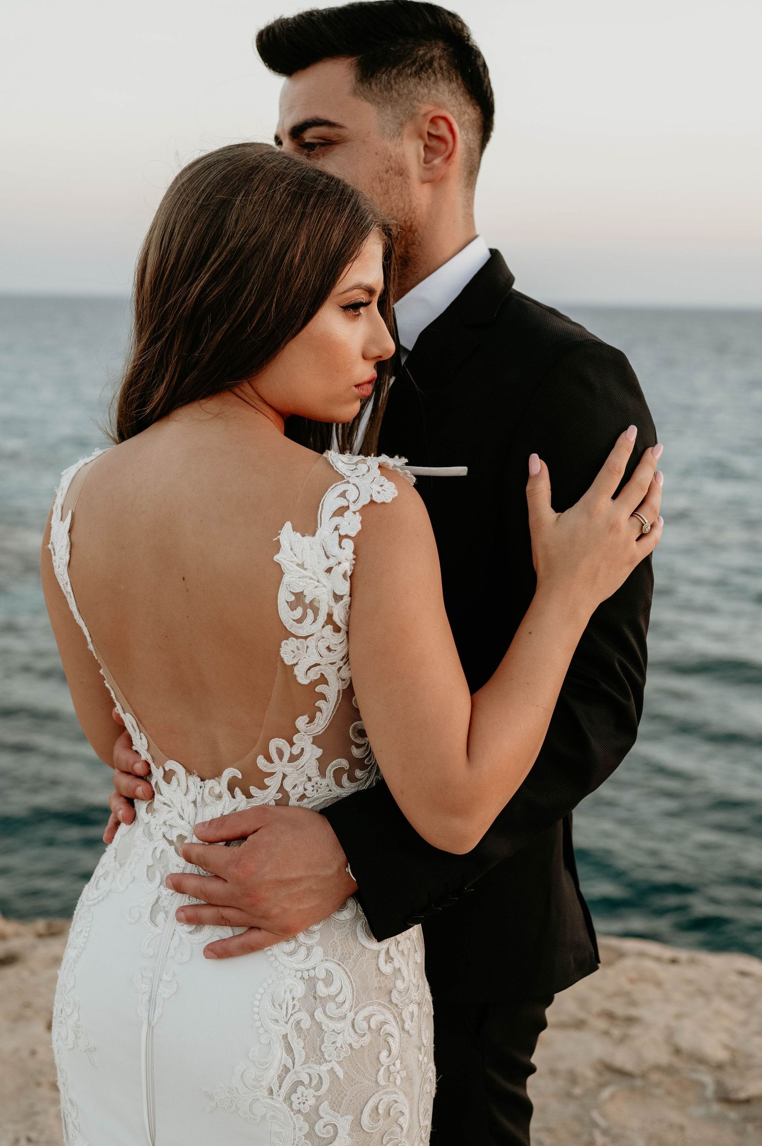 A romantic beachside photo series showing intimate wedding couple poses against an ocean backdrop at sunset.