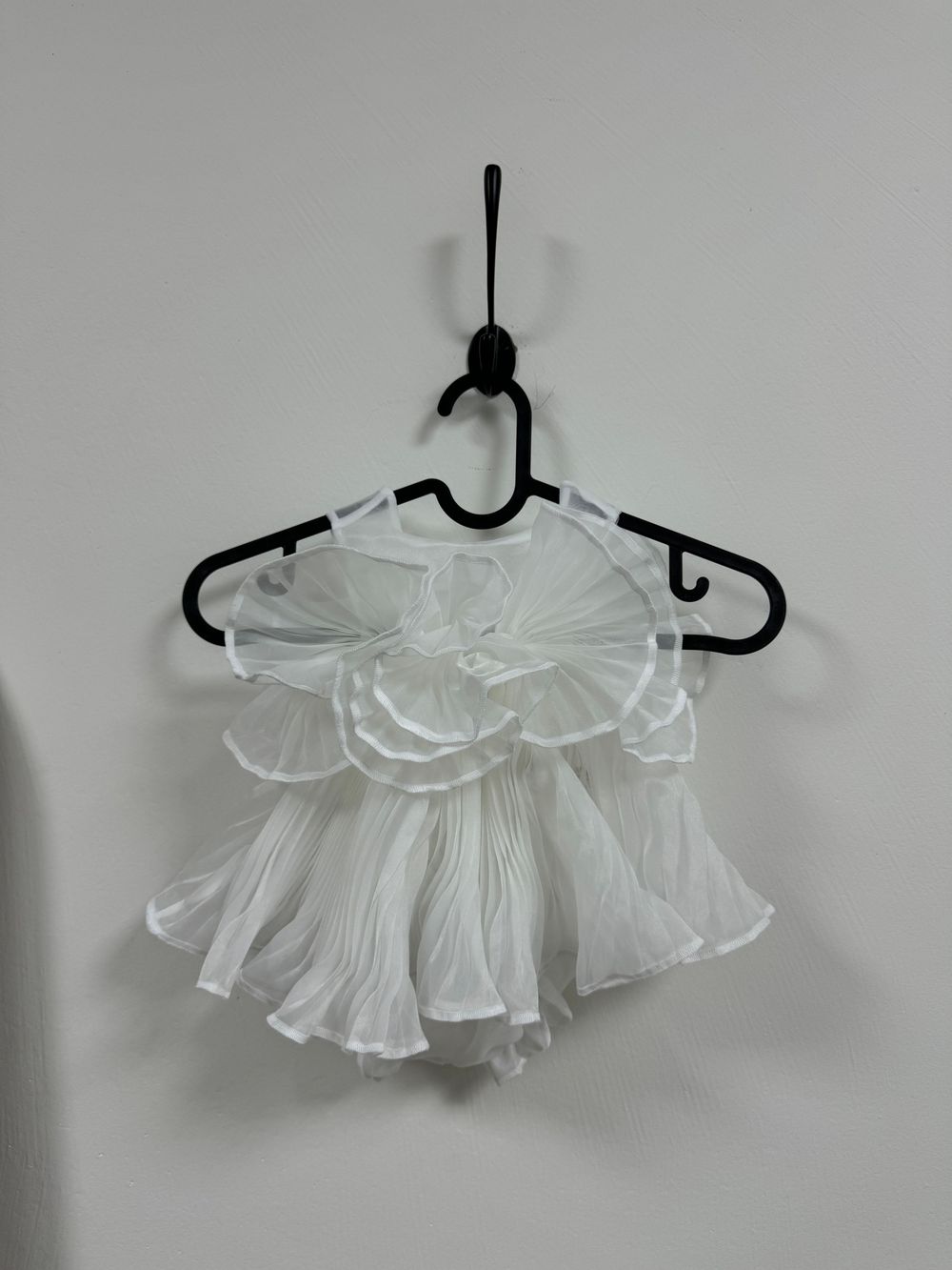 White sheer ruffled detachable collar displayed on multiple black hangers against a light background.