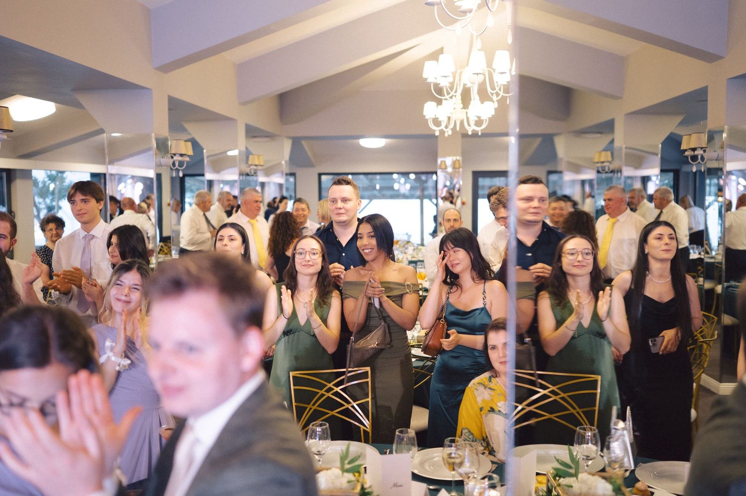 Wedding reception guests celebrate with raised hands and joyful expressions during a party.
