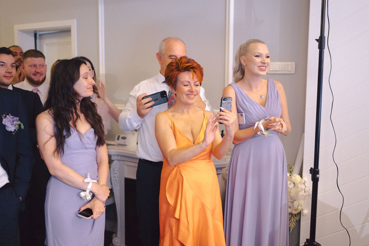 Group of wedding guests dance and interact at a lively indoor reception event.